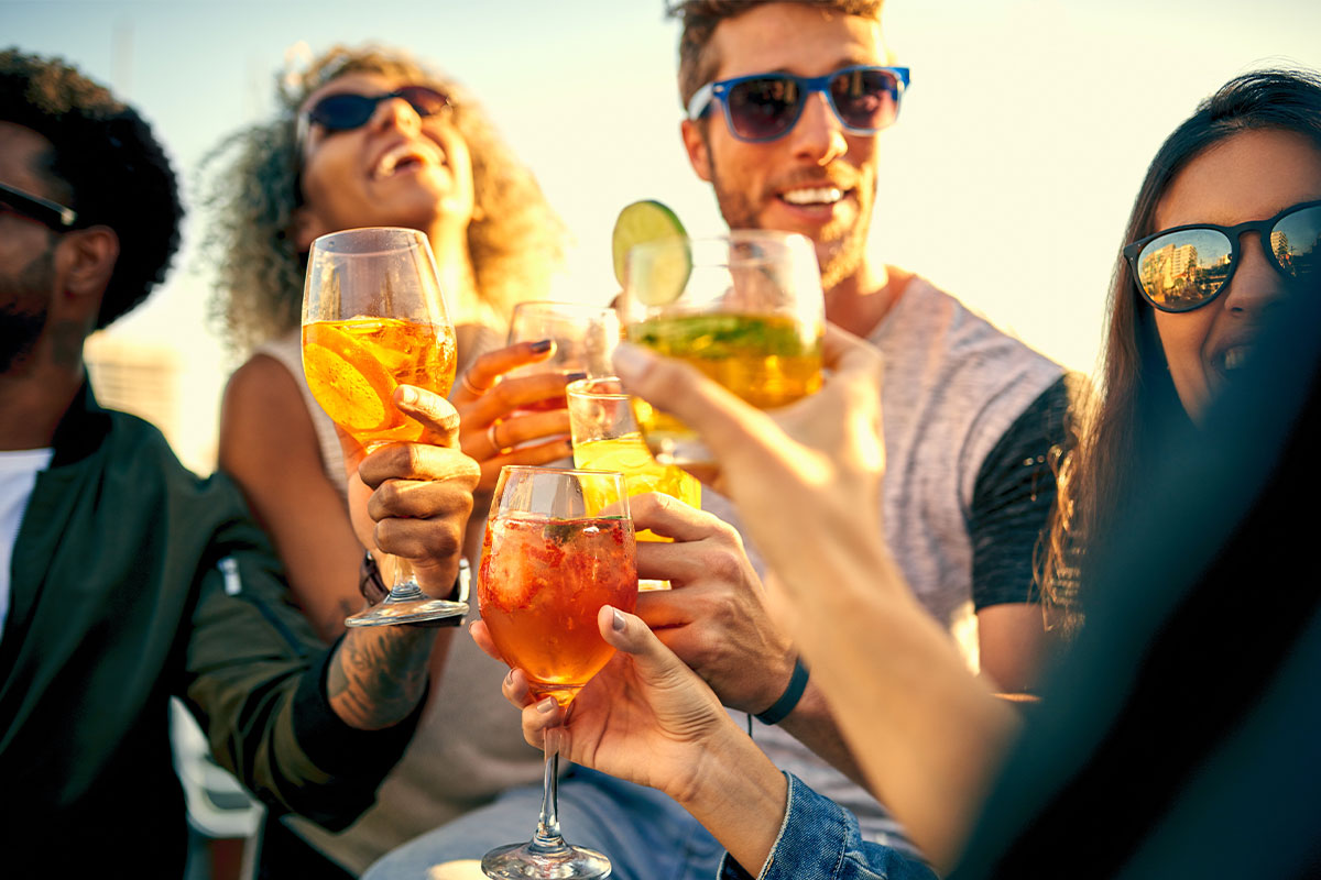 Menschen stoßen mit Cocktails bei einer Sommerveranstaltung in der Arkona Sky Bar auf Rügen an.