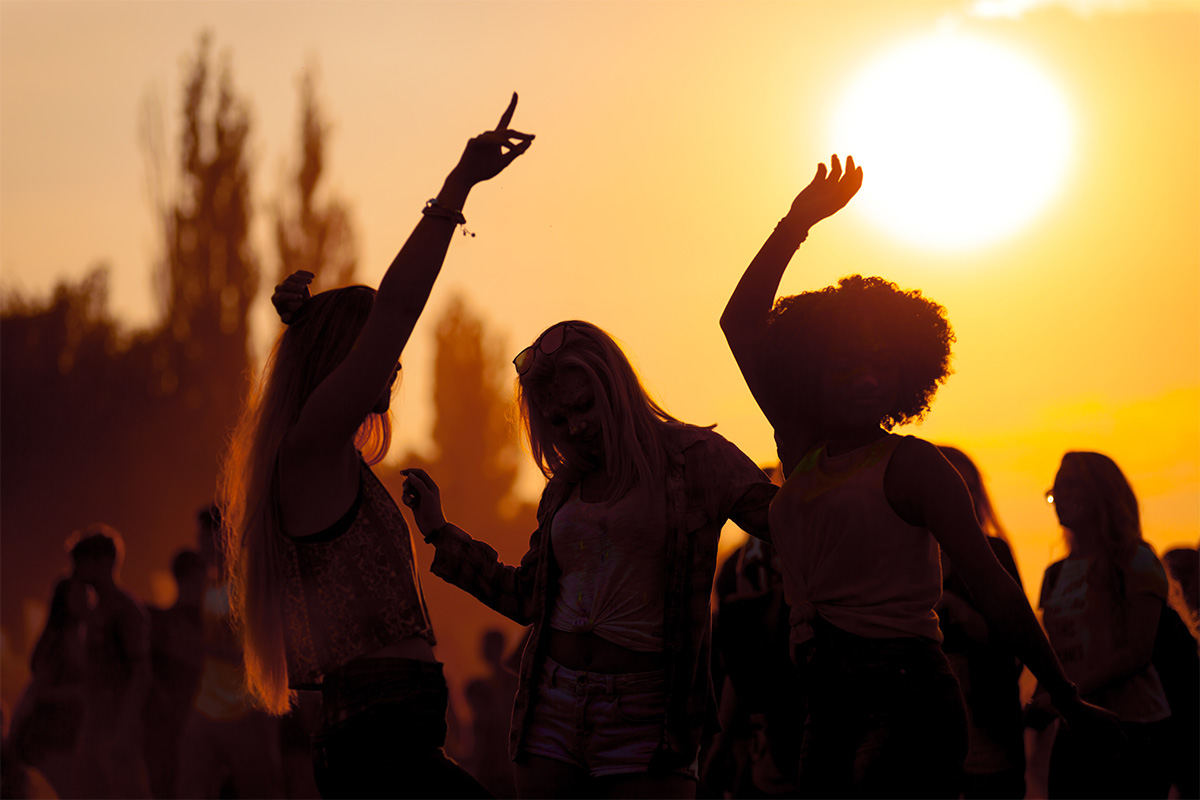 Tanzende Menschen im Sonnenuntergang bei einem Sommer-Event in der Arkona Sky Bar auf Rügen.