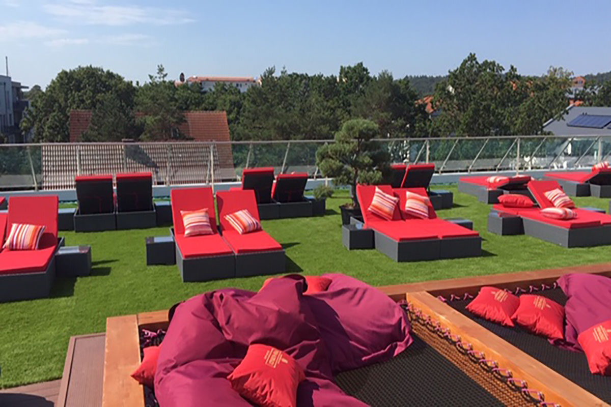 Rote Sonnenliegen auf der Dachterrasse der Arkona Sky Bar auf Rügen mit Blick über die Dächer von Binz.