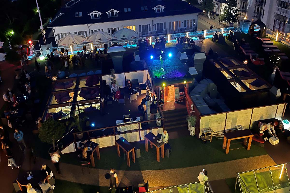 Abendveranstaltung mit Musik und Lichtern auf der Dachterrasse der Arkona Sky Bar mit Sommergästen auf Rügen.