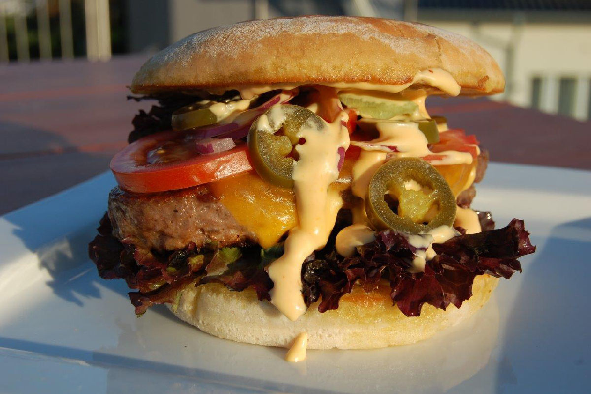 Burger mit Jalapeños, Tomaten, Salat und cremiger Sauce auf einem Teller in der Arkona Sky Bar auf Rügen im Sommer.